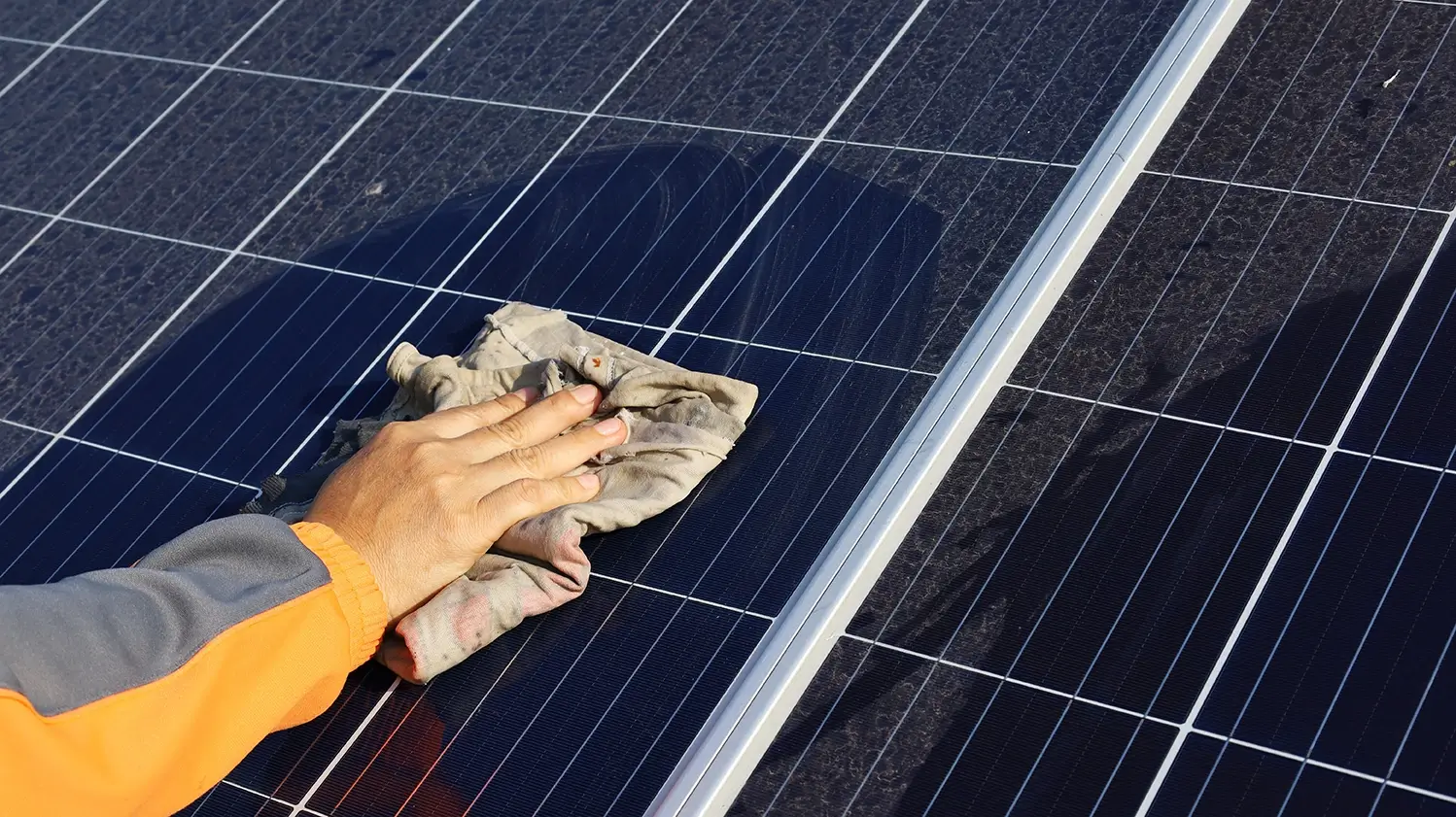 Hand cleaning solar panels with towel